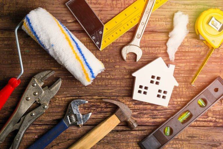 property maintenance tools laid out on a wooden surface with a house in the middle